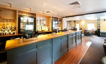 "a large , empty bar with a wooden counter and a sign that says "" canary "" on the wall" at Premier Inn Bristol East (Emersons Green)