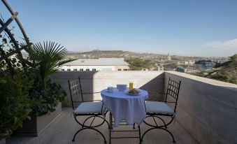 a table with a white tablecloth and two chairs is set up on a balcony overlooking a cityscape at Citrus Hotel