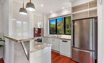 a modern kitchen with white cabinets , stainless steel appliances , and a large window overlooking a forest at Sand Dunes Resort