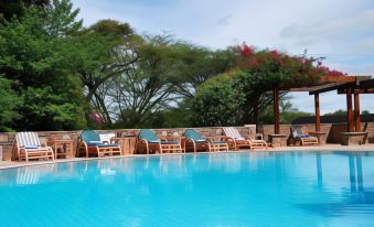 a large outdoor swimming pool surrounded by chairs and tables , providing a relaxing atmosphere for guests at Muthu Keekorok Lodge, Maasai Mara, Narok