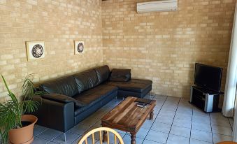 a living room with a black leather couch , wooden coffee table , and brick walls , featuring a flat - screen tv mounted on the wall at Chalets on Stoneville