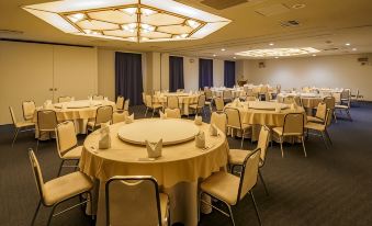 a large dining room with multiple round tables and chairs arranged for a formal event at Airline Hotel