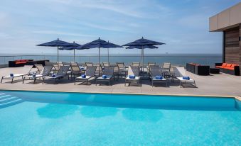 a large pool with lounge chairs and umbrellas set up next to it , overlooking the ocean at Allegria Hotel