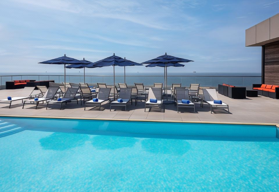 a large pool with lounge chairs and umbrellas set up next to it , overlooking the ocean at Allegria Hotel