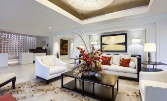 a modern living room with a white couch , coffee table , and chandelier , decorated with floral arrangements and artwork at The H Hotel