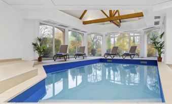 an indoor swimming pool with a large window , surrounded by lounge chairs and a patio area at Club Wyndham Normandy