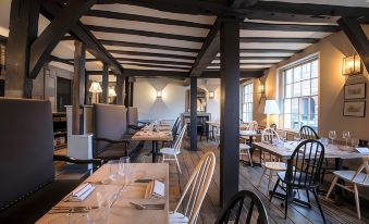 a modern restaurant interior with wooden beams , white tables , and chairs , as well as large windows and dining area at The Crown