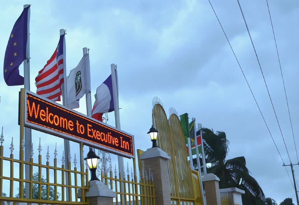 "a hotel entrance with multiple flags and a sign that reads "" welcome to the executive inn .""." at Executive Inn