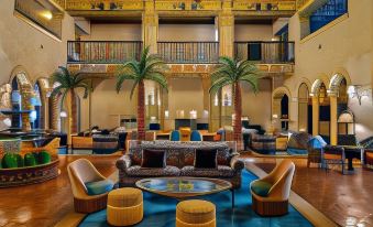 a modern hotel lobby with high ceilings , colorful seating arrangements , and palm trees , creating an inviting atmosphere at The Hollywood Roosevelt