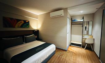 a modern hotel room with wooden flooring , white walls , and a black bed with blue bedding at Monaco Hotel