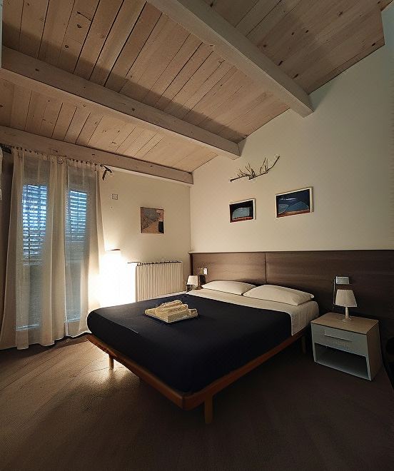 a modern bedroom with wooden ceiling , white walls , and a large bed with a blue comforter at Memento
