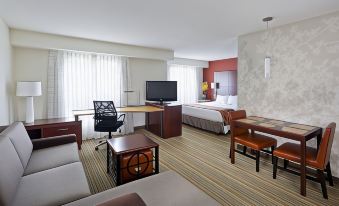 a modern hotel room with a large bed , desk , and couch , as well as a living area with a couch and coffee table at Residence Inn Lansing West