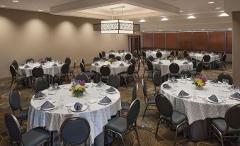 a well - decorated banquet hall with multiple tables and chairs , each set for a meal , under a hanging light fixture at DoubleTree by Hilton Hotel Murfreesboro