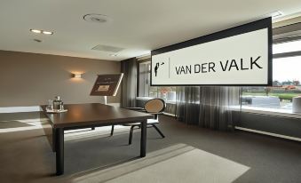 "a large screen displays the words "" van der valk "" in multiple languages , including english and french , in a room with a table and" at Van der Valk Hotel Volendam