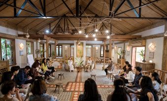 a group of people are sitting in a room with wooden beams and chairs , looking at each other at Tam Coc Garden Resort