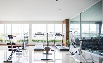 a well - equipped gym with various exercise equipment , including treadmills and weightlifting machines , set up in a spacious room with large windows at Bay Hotel Srinakarin