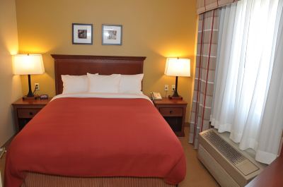 a hotel room with a red bedspread , white pillows , and a window with curtains , along with a lamp and two framed pictures on the at Country Inn & Suites by Radisson, Watertown, SD
