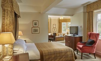 a hotel room with a king - sized bed , a flat - screen tv , and a chair in the corner at Macdonald Berystede Hotel and Spa