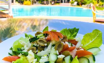 a plate of greek salad with lettuce , tomato , and olive , placed next to a swimming pool at Thunderbird Resorts - Rizal