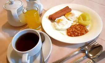 a breakfast table with a cup of coffee , a plate of food , and various utensils at Terrace Hotel