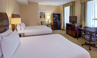 a hotel room with two beds , a desk , and a window , all neatly arranged in the space at Hilton Garden Inn Jackson Downtown