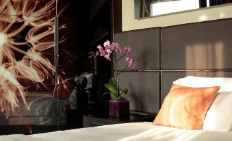 a woman lying on a bed with an orchid in a vase next to her at Park Plaza Westminster Bridge London