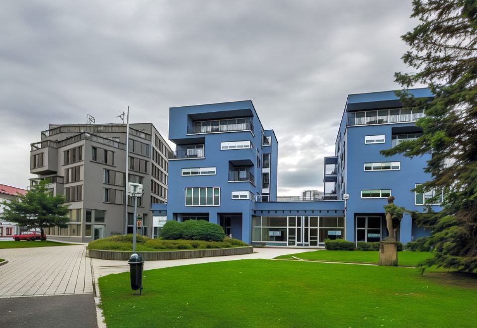 a modern blue building with multiple floors and balconies , surrounded by green grass and trees at Hotel 99