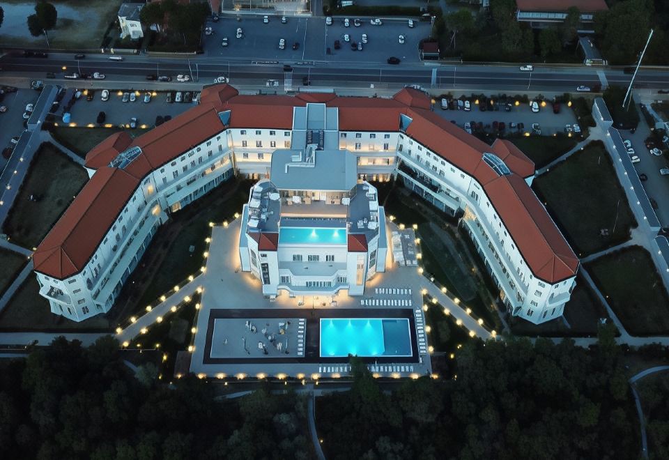 an aerial view of a large white building with red roofs and a swimming pool in the center at Toscana Charme Resort