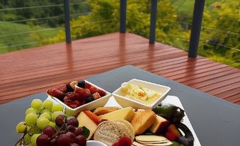 a tray of food with various fruits and cheeses on a table with a scenic view at Top of the Hill