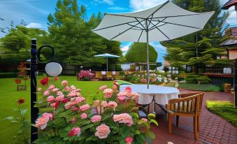 a lush green lawn with a dining table , chairs , and an umbrella set up for a meal at Villa Rosa