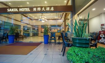 "a hotel entrance with a sign that reads "" hotel "" and several potted plants on either side of the door" at Sakol Hotel