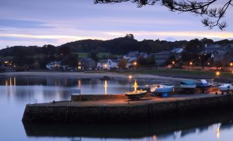 a serene night view of a small town with houses , trees , and water , captured during the blue hour at Aberdour Hotel, Stables Rooms & Beer Garden