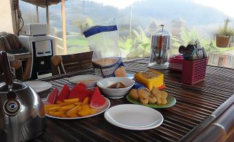 a table with a variety of food items , including fruits , bread , and other snacks , placed on a wooden surface at De Salak Homestay