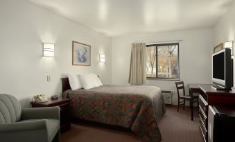 a hotel room with a bed , two nightstands , and a window , all lit by natural light at Days Inn by Wyndham Stoughton WI.