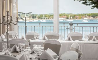 a restaurant with white chairs and tables set up for a formal event , overlooking a body of water at Langstone Quays Resort