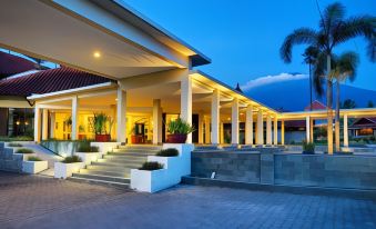 a large white building with a courtyard , possibly a restaurant or a hotel , surrounded by palm trees at Horison Tirta Sanita Kuningan