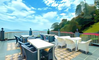 an outdoor dining area with a view of the ocean , featuring white tables and chairs at Wood Stock Kasauli - Rooms & Cottages - Panoramic View & Balcony Rooms