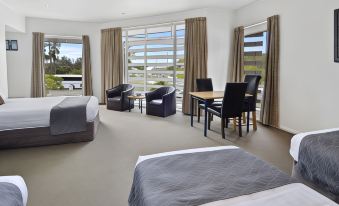 a modern hotel room with two beds , a dining table , and chairs near a window at Poenamo Hotel