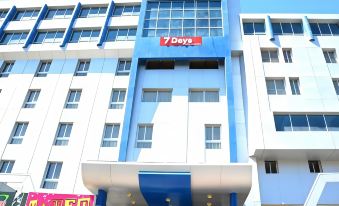 "a modern office building with the name "" 7 days "" on the front , surrounded by greenery and a clear blue sky" at Seven Days Hotel