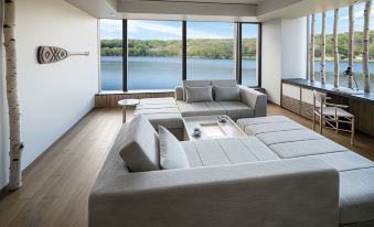 The living room features large windows and modern furniture, including couches that offer a view of the water at Hoshino Resorts KAI Poroto