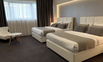 a modern hotel room with two beds , a desk , and a window , all decorated in white and gray at Hotel Leone