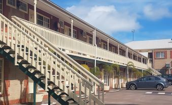 a building with a white staircase and cars parked in front of it , under a blue sky at Motel Goolwa