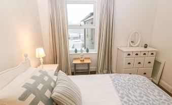 a bedroom with a white bed , curtains , and a window looking out onto a street at Avondale