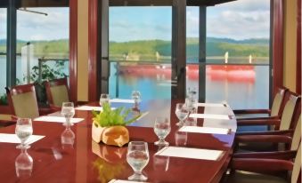 a large dining table with wine glasses and a bottle of wine on it , set for a meal at Crest Hotel