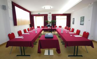 a conference room set up for a meeting , with several chairs arranged in a semicircle around a table at Best Western Cesena Hotel