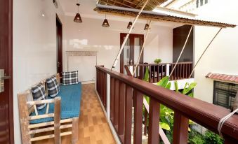 a room with a wooden floor and a couch is shown with a railing in the foreground at Pink Beach Homestay