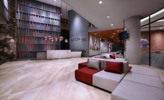 a modern hotel lobby with red and white furniture , including couches and chairs , arranged around a reception desk at ASTON Inn Mataram