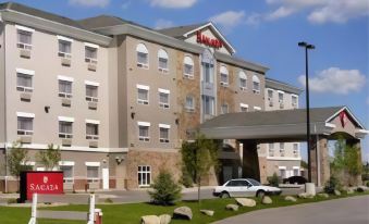 "a large hotel building with a red sign that says "" niles inn & suites "" is shown" at Ramada by Wyndham High River