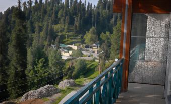 a wooden balcony with a view of a forested area and a small town in the distance at Summit Hotel