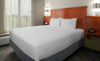 a large bed with white sheets and a wooden headboard is in a room with a window at Hyatt Place Pittsburgh Airport/Robinson Mall